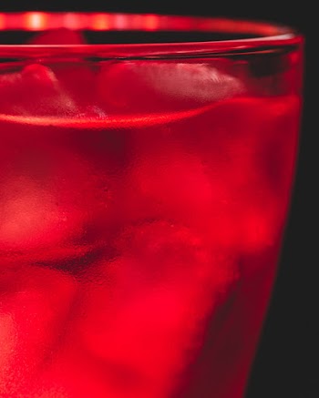 Close-up Photo of Red Beverage Full of Ice Cubes In Front of Black Background