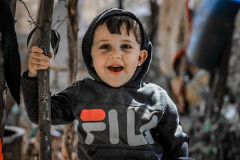 Close-up Photo of Smiling Boy in Grey Fila Hoodie