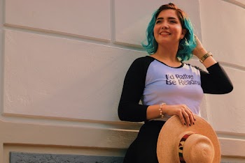 Close-up Photo of Smiling Woman in White and Black Raglan 3/4-sleeved T-Shirt Standing By White Wall