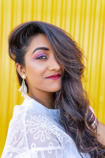 Close-up Photo of Smiling Woman in White Floral Lace Top Posing In Front of Yellow Background