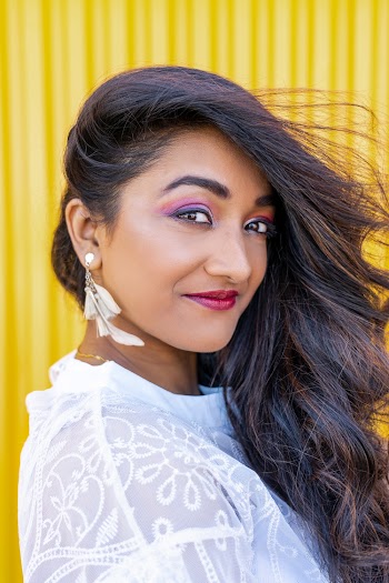 Close-up Photo of Smiling Woman in White Floral Lace Top Posing In Front of Yellow Background