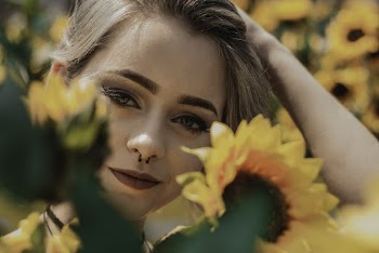 Close-up Photo of Smiling Woman Posing by Yellow Sunflowers