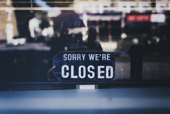 Close-Up Photo of Sorry We're Closed Sign on Glass Window