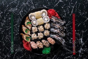 Close Up Photo of  Sushi on Black Plate Beside Red and Green  Chopsticks