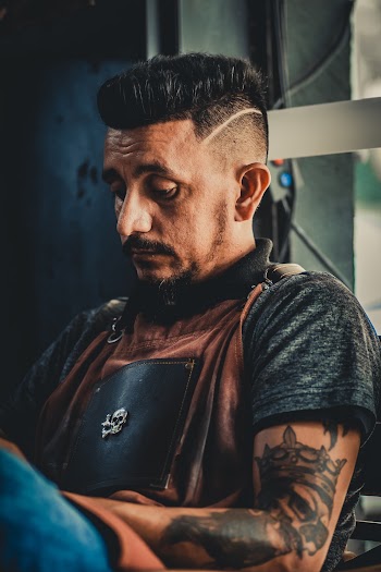 Close-up Photo of Tattooed Man in Black and Brown T-shirt Sitting