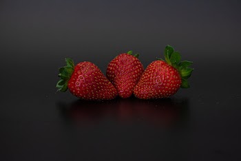 Close-up Photo of Three Red Strawberries on Black Surface