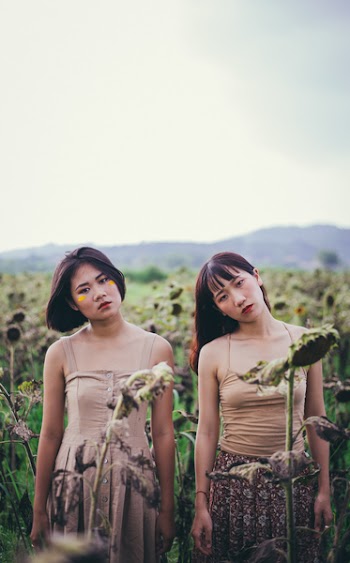 Close-up Photo of Two Women Standing on Sunflower Field