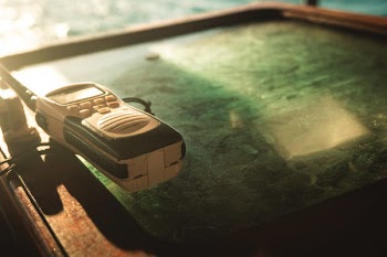 Close-up Photo of White and Black Two-way Radio on Green Glass Surface