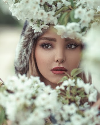 Close-up Photo of Woman's Face Behind White Flowers