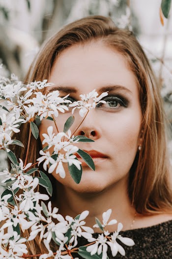 Close-Up Photo of Woman's Face Near Flowers