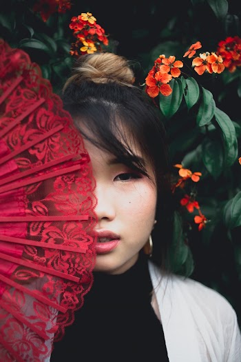 Close-Up Photo of Woman Covering Face With Red Hand Fan