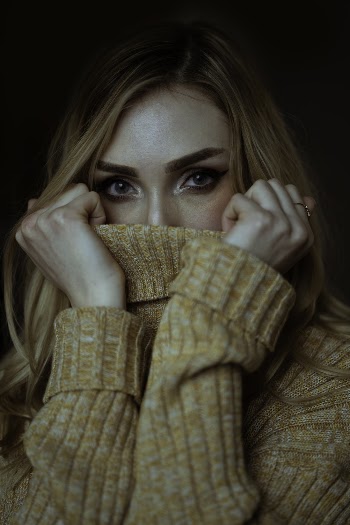Close-up Photo of Woman Covering Her Mouth with a Brown Sweater