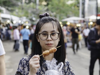 Close-Up Photo of Woman Eating Street Food