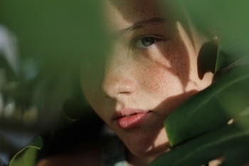 Close-up Photo of Woman Hiding Behind Green Leaves