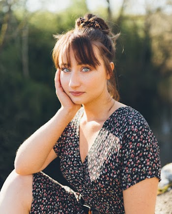 Close-up Photo of Woman Holding Her Cheek While Sitting on Rocks