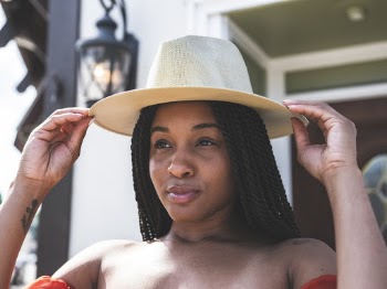 Close-Up Photo of Woman Holding Her Hat With Two Hands