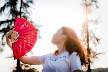 Close-up Photo of Woman Holding Red Hand Fan