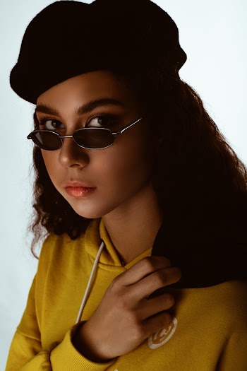Close-up Photo of Woman in Black Beret Hat, Sunglasses, and Yellow Hoodie Posing
