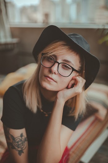 Close-up Photo of Woman In Black Hat and T-shirt Resting Her Head on Her Left Hand
