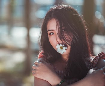 Close-up Photo of Woman in Brown Sleeveless Top With White Daisy Flower