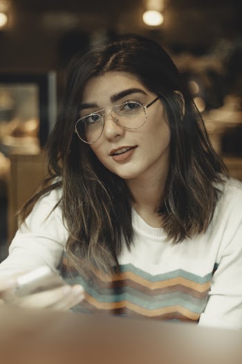 Close-up Photo of Woman in Glasses Sitting at a Coffee Shop