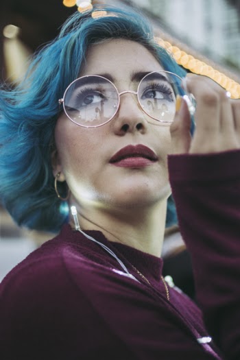 Close-up Photo of Woman in Purple Top with Blue Hair Holding String Lights