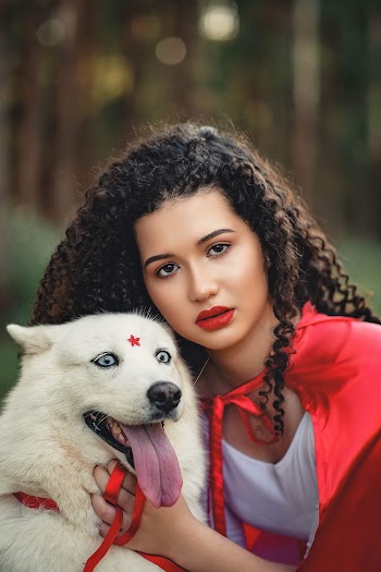 Close-up Photo of Woman in White Dress and Red Cape Posing Next to White Dog