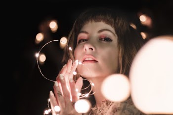 Close-up Photo of Woman Posing while Holding Lit String Lights