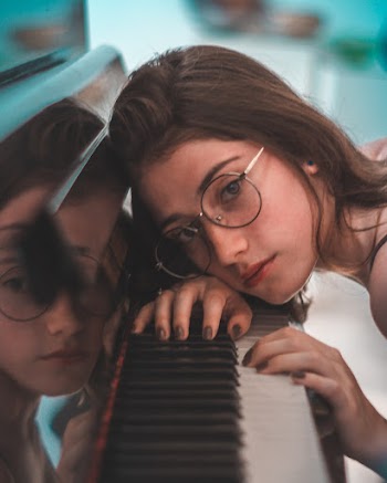 Close-up Photo of Woman Resting Head on Grand Piano Keys
