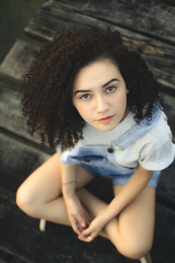 Close-up Photo of Woman Sitting on Wooden Surface While Looking up