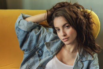 Close-up Photo of Woman Sitting on Yellow Chair Posing