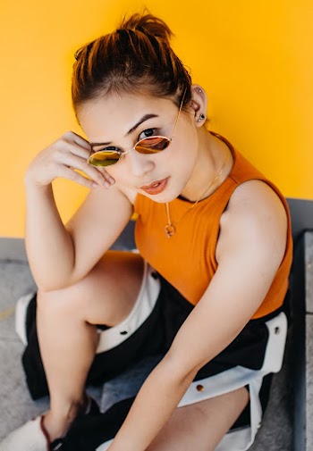 Close-up Photo of Woman Squat Posing Beside Yellow Wall