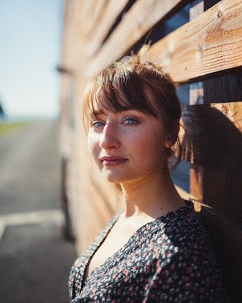Close-up Photo of Woman Standing in Front of Brown Wooden Wall