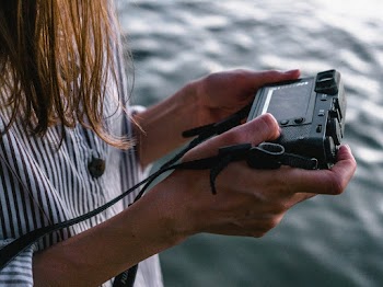 Close-up Photo of Woman Viewing Photos from Her Camera Near Body of Water