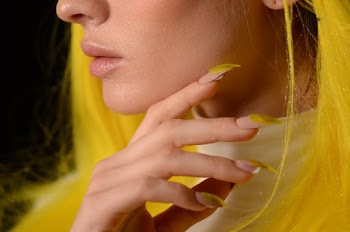 Close-up Photo of Woman With Yellow, Glitter on Her Face, and Yellow Nails