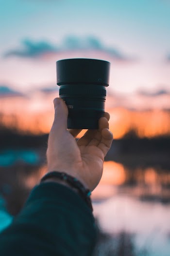 Close-Up Photography of a Person Holding Camera Lens