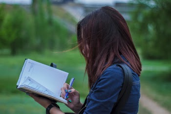 Close-Up Photography of a Person Writing on Notebook