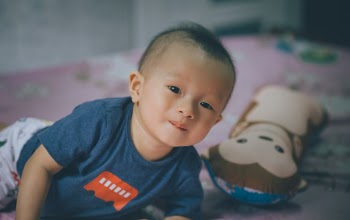 Close-Up Photography of Baby Lying on the Bed Near Bolster Pillow