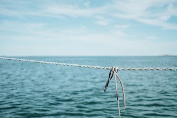 close-up photography of grey rope near body of water