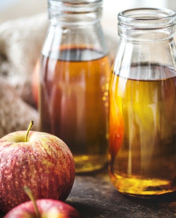 Close-up Photography of Honeycrisp Apples and Two Clear Glass Bottles Filled With Liquid