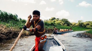 Close-up Photography of Man Holding Wooden Paddle Riding on Blue Boat