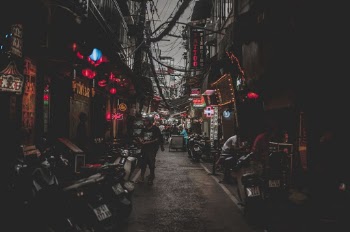 Close-up Photography of People Sitting and Standing Between Buildings
