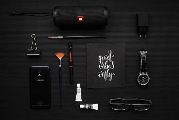 Close-up Photography of Smartphone Beside Binder Clip, Speaker and Eyeglasses on Black Textile