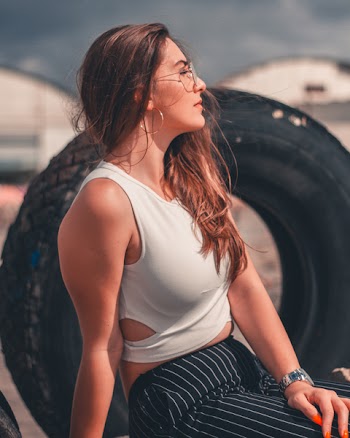 Close-up Photography of Woman Wearing White Sleeveless Crop-top and Black-and-white Striped Bottoms Sitting on Chair