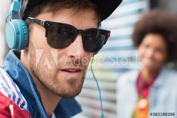 Close up portrait cool young man with headphones and sunglasses
