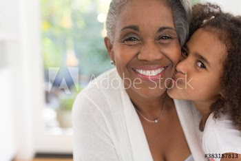 Close up portrait cute granddaughter kissing grandmother on cheek
