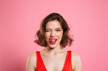 Close-up portrait of pretty playful woman winks one eye, showing tongue, , isolated on pink Free Photo