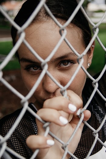 Close-up Portrait Photo of Woman Leaning on Chain-link Fence