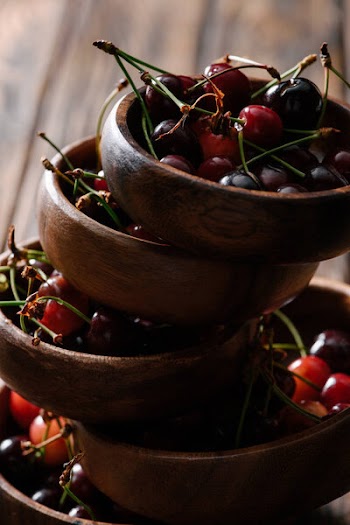 Close-up view of stacked bowls with fresh ripe cherries on wooden table