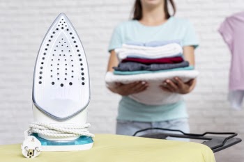 Close-up woman carrying clothes to the ironing board Free Photo